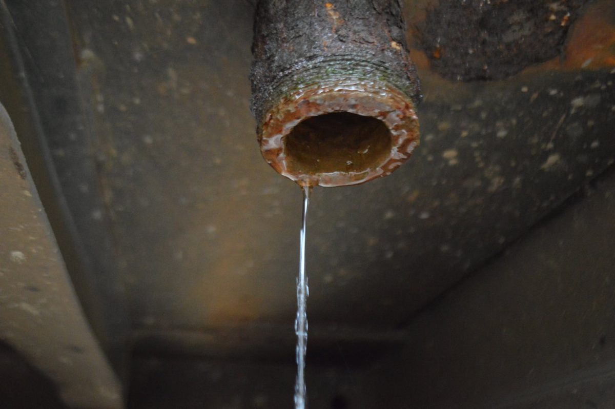 Тихо течет вода. Ржавые водопроводные трубы. Трубы по которым течет вода из под крана. Старые трубы. Ржавая труба.