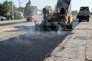 Асфальтоукладчик распределяет горячую смесь по бетонным плитам