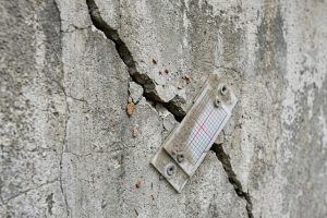 Диагональная трещина в бетонной стене с установленным маяком
