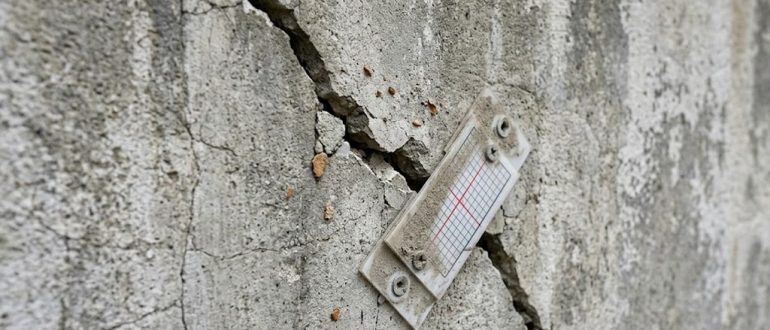 Диагональная трещина в бетонной стене с установленным маяком