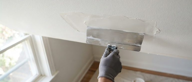 Шпаклёвка небольшого дефекта на белом потолке широким шпателем
